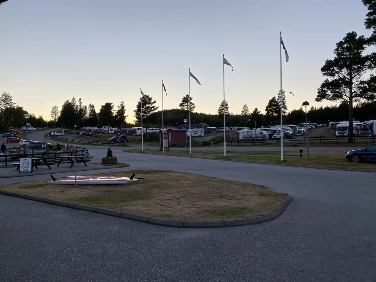 En asfalterad parkeringsplats vid Gullviks havsbad camping & stugby, med flera husbilar och skåpbilar parkerade. En gatlykta och en lyktstolpe syns i bakgrunden.