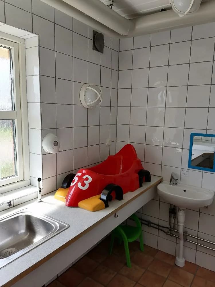 Bild av ett badrum på Jägersbo Camping Swecamp, med en vit tvättställ monterad i en vägghängd enhet. På golvet ligger klinkerplattor och intill tvättstället finns en modern kran. Badrummet har ett enkelt och rent utseende.