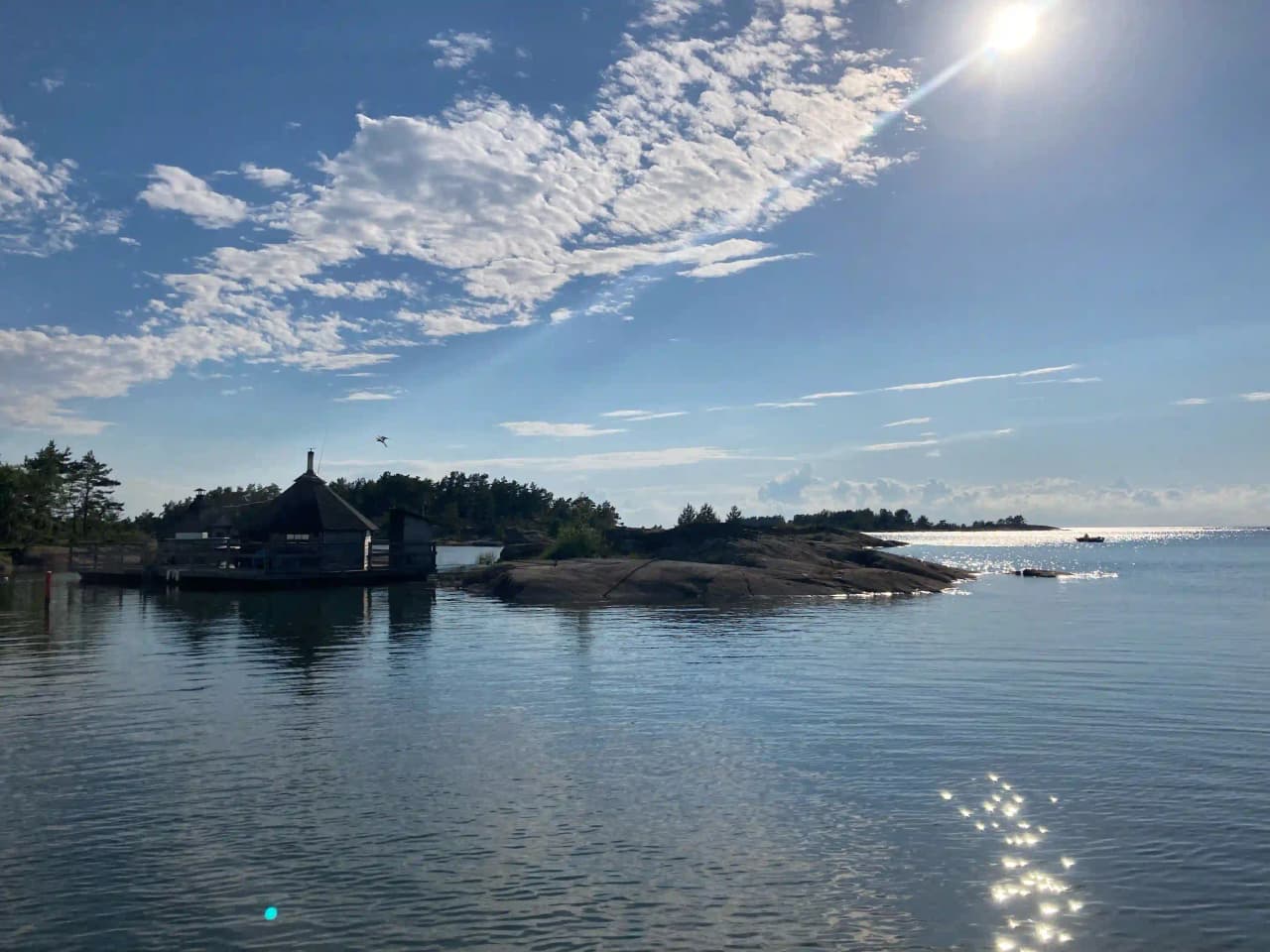En vy över Filsbäcks camping visar en klar himmel ovanför en sjö med omgivande stränder och molnformationer.
