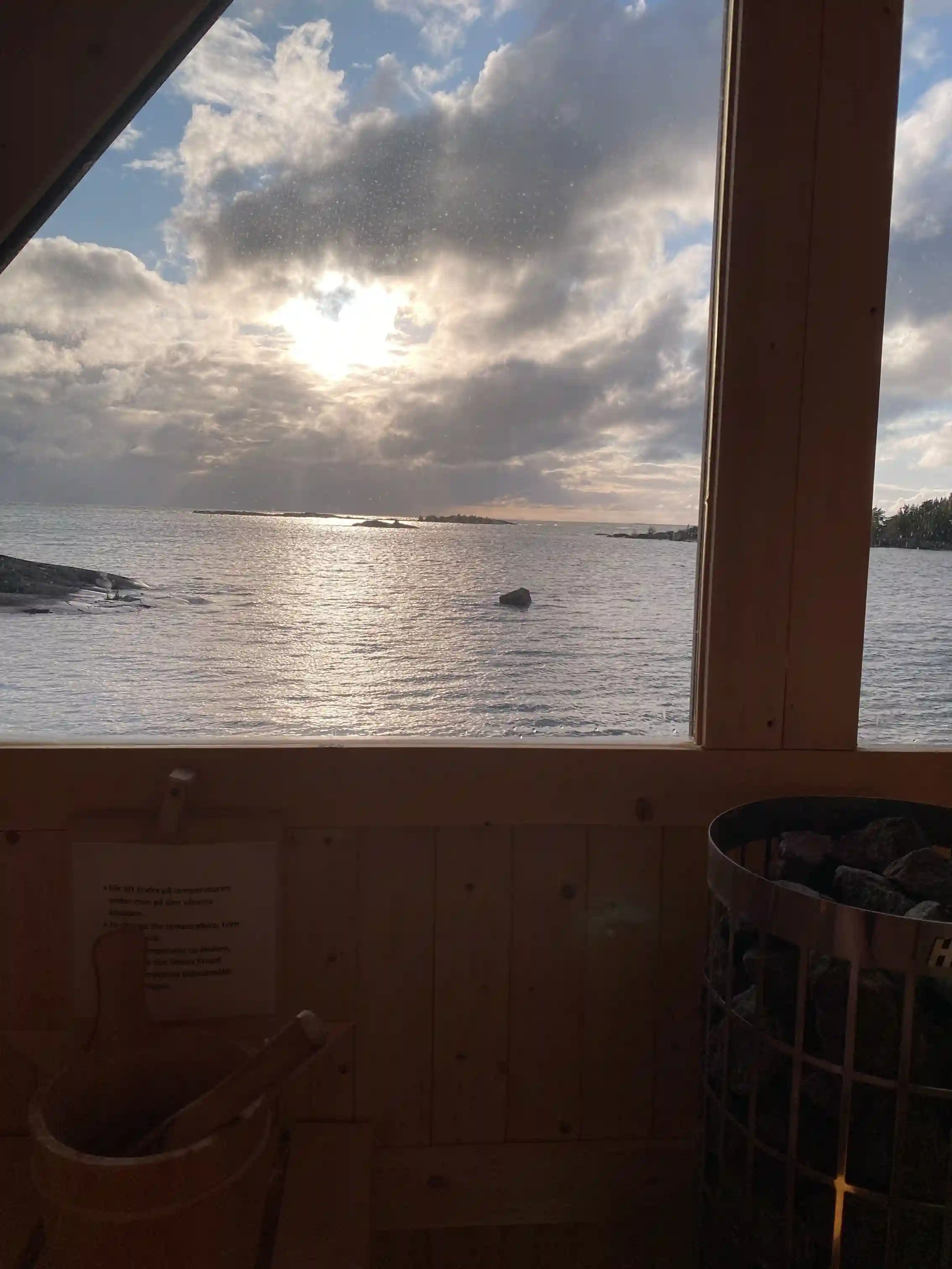 En solnedgång vid Filsbäcks camping med havet i förgrunden. Solens gyllene strålar reflekteras på vattenytan och himlen är färgad i mjuka nyanser av orange och rosa när dagen övergår i kväll.