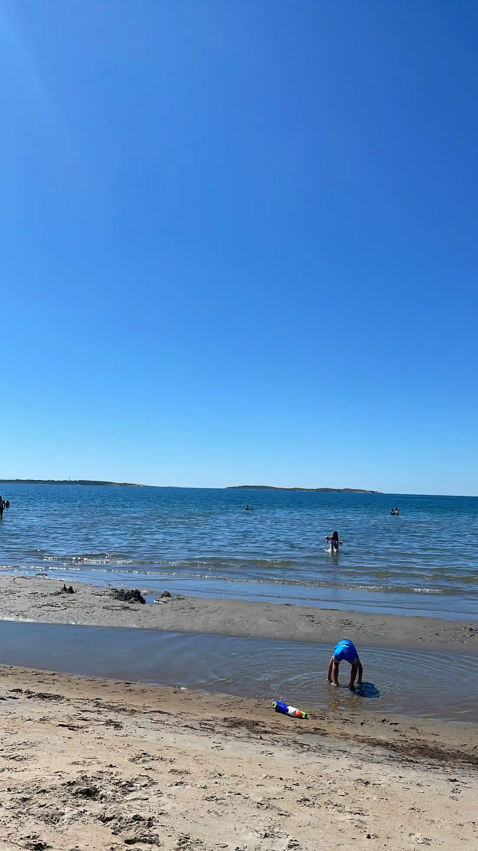 En härlig strandbild vid Åsa Camping & Havsbad med blått hav, vid horisonten och sandig kust där besökare njuter av solen och havet.