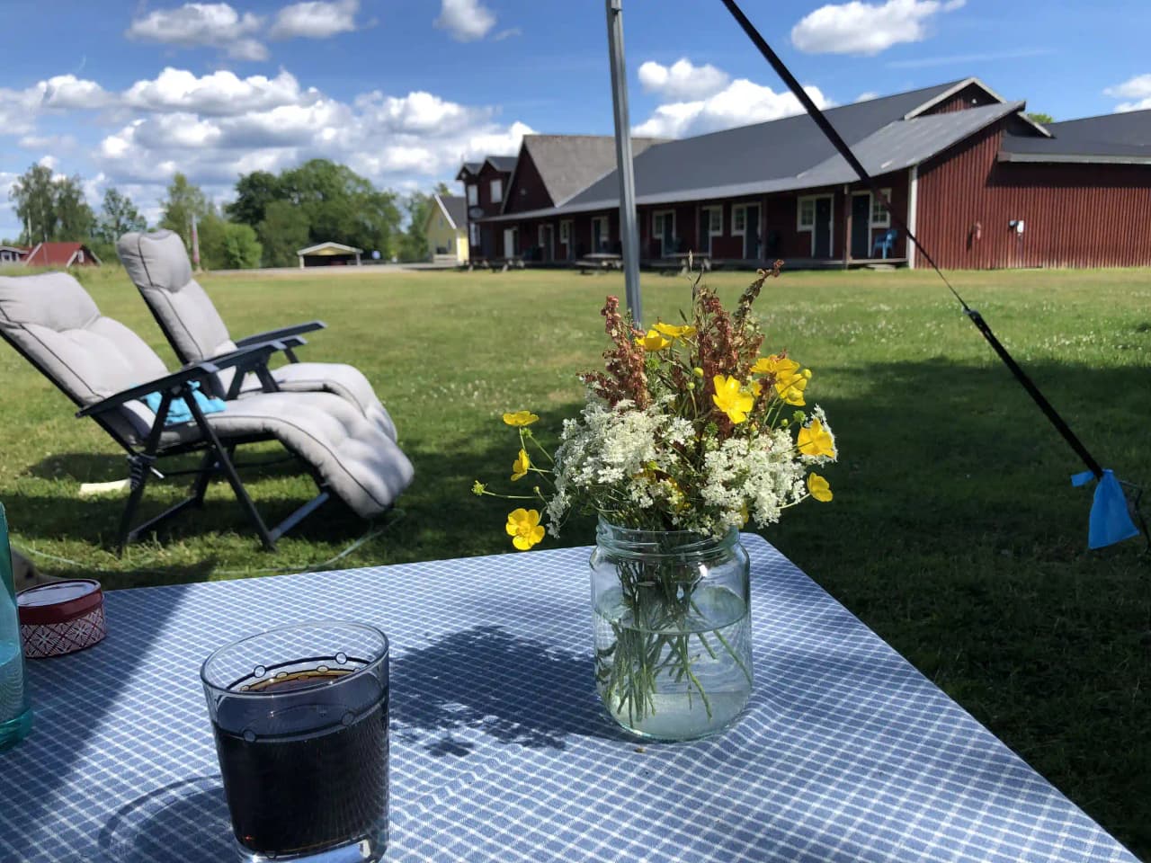 En grön gräsmatta med utomhusmöbler, inklusive stolar och ett bord, står i skuggan på Abrahams Camp, vilket erbjuder en plats för avkoppling och fritid.
