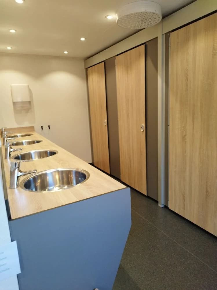 En interiörbild från Våmåbadets camping som visar ett rum med trägolv och träväggar. Rummet har även ett träinnertak och en synlig VVS-armatur. Atmosfären är varm och inbjudande tack vare de naturliga träinslagen.