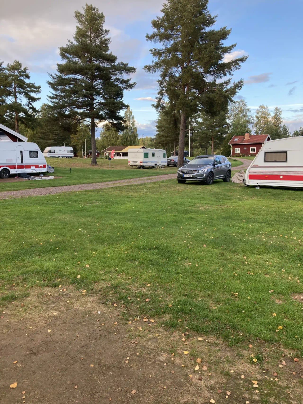 En campingplats vid Grebbestadfjorden med flera husbilar och husvagnar parkerade på en grön gräsyta under en skymningshimmel med lätta moln.