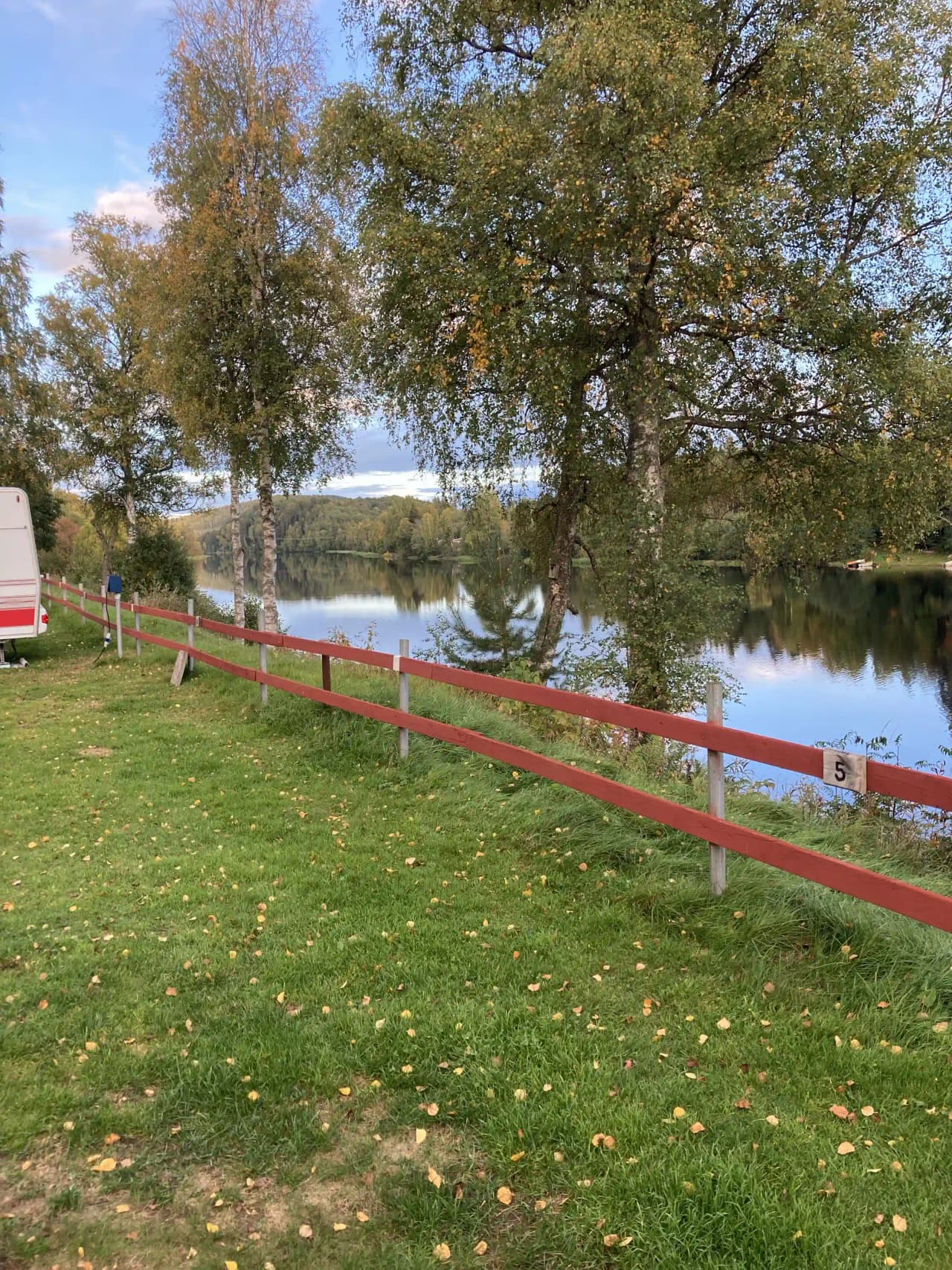 En grön gräsmatta med staket kring en park vid Grebbestadfjorden.