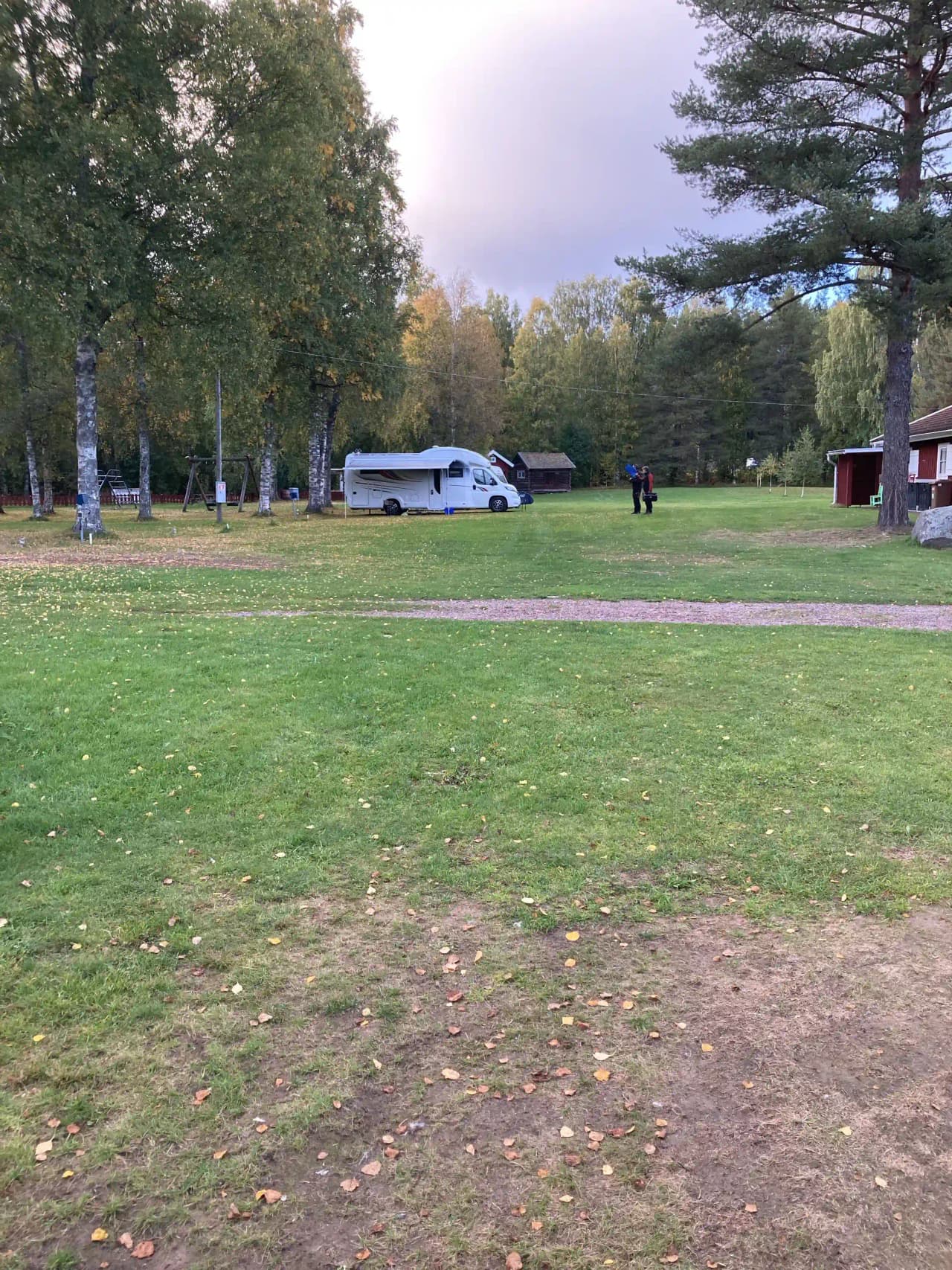 En grön campingplats vid Grebbestadfjorden med gräs, träd och öppna ytor, perfekt för utomhusaktiviteter och avkoppling i naturen.