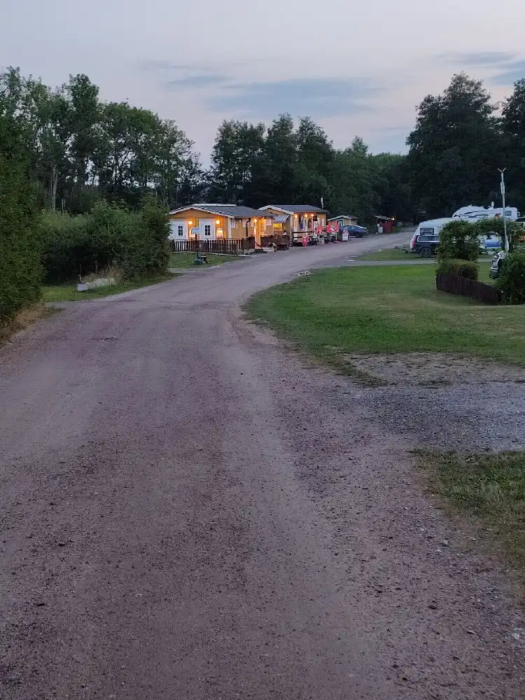 En bild av en campingplats på Sundbyholms camping med flera husbilar och husvagnar parkerade på en grusad uppfart.