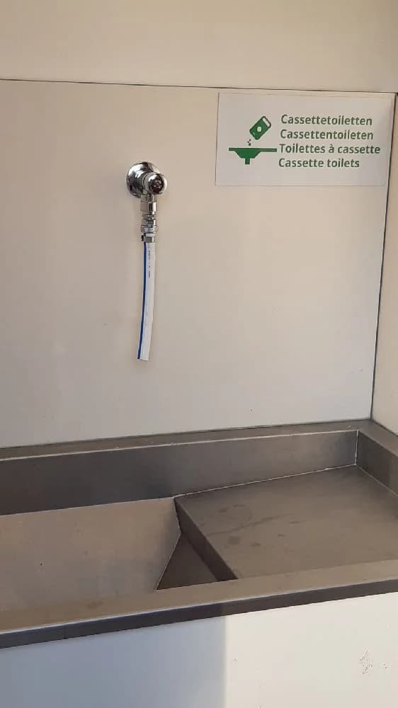 Alt-text: Ett modernt och stilrent badrum med en skinande ren handfatinstallation. Kromad kran och blandare i rostfritt stål, omgiven av blanka kakelplattor, vilket ger en känsla av elegans och renlighet vid Hofsnäs herrgård.