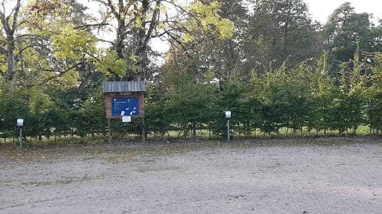 En grönskande park vid Hofsnäs Herrgård, med stigar som slingrar sig genom träd och buskar.