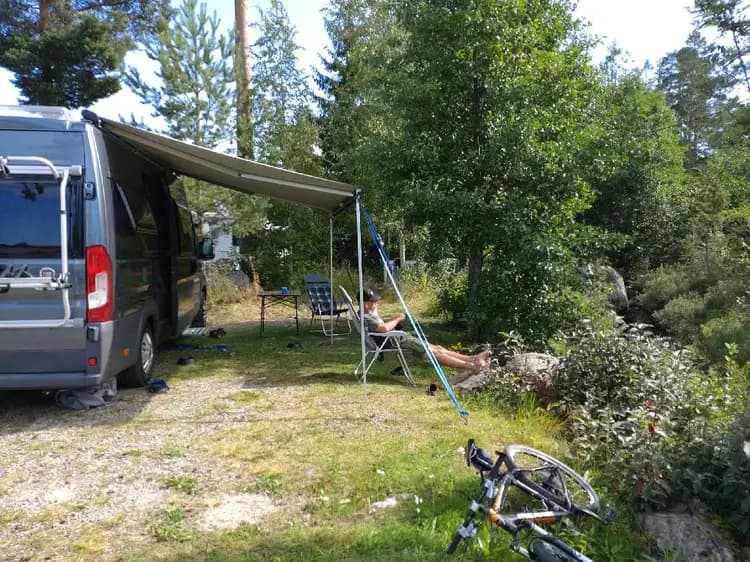 En familjebuss parkerad vid Skärså Camping, utrustad med en takräcke för bagage. I bakgrunden syns campingområdet.