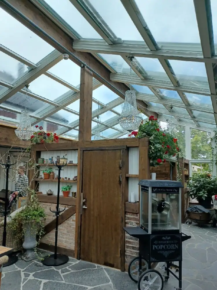 Bild på hotellets spaområde vid Lögnäs gård. Träelement och järndetaljer skapar en rustik atmosfär, kompletterat med blomkrukor och gröna växter. Ljuset strömmar in från glastak, vilket ger en naturlig känsla till rummet.