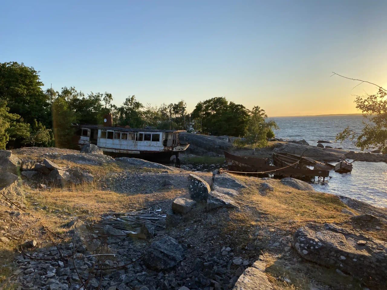 En kustnära vy vid Stenbräckagården Hägnan med klippor, en båt vid strandkanten och en öppen havsutsikt i bakgrunden.