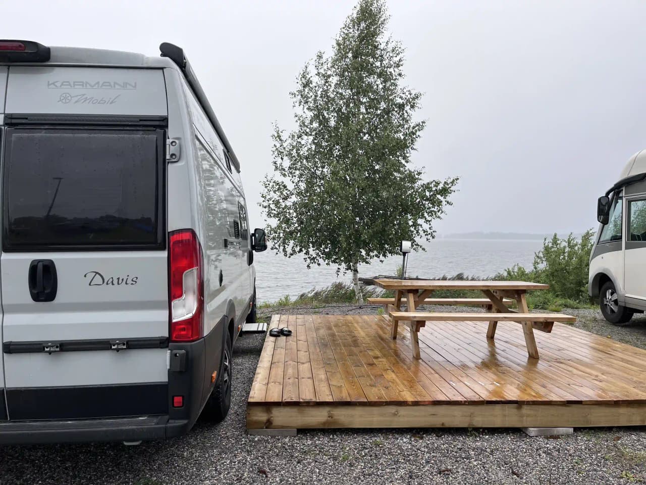 En småbåtshamn med parkerade fritidsfordon och skåpbilar längs vattnet i Arvika.