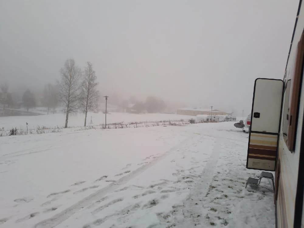 En vinterdag vid Bygdsiljums camping, täckt av snö och omgiven av dimma, skapar en mystisk och kylig atmosfär.