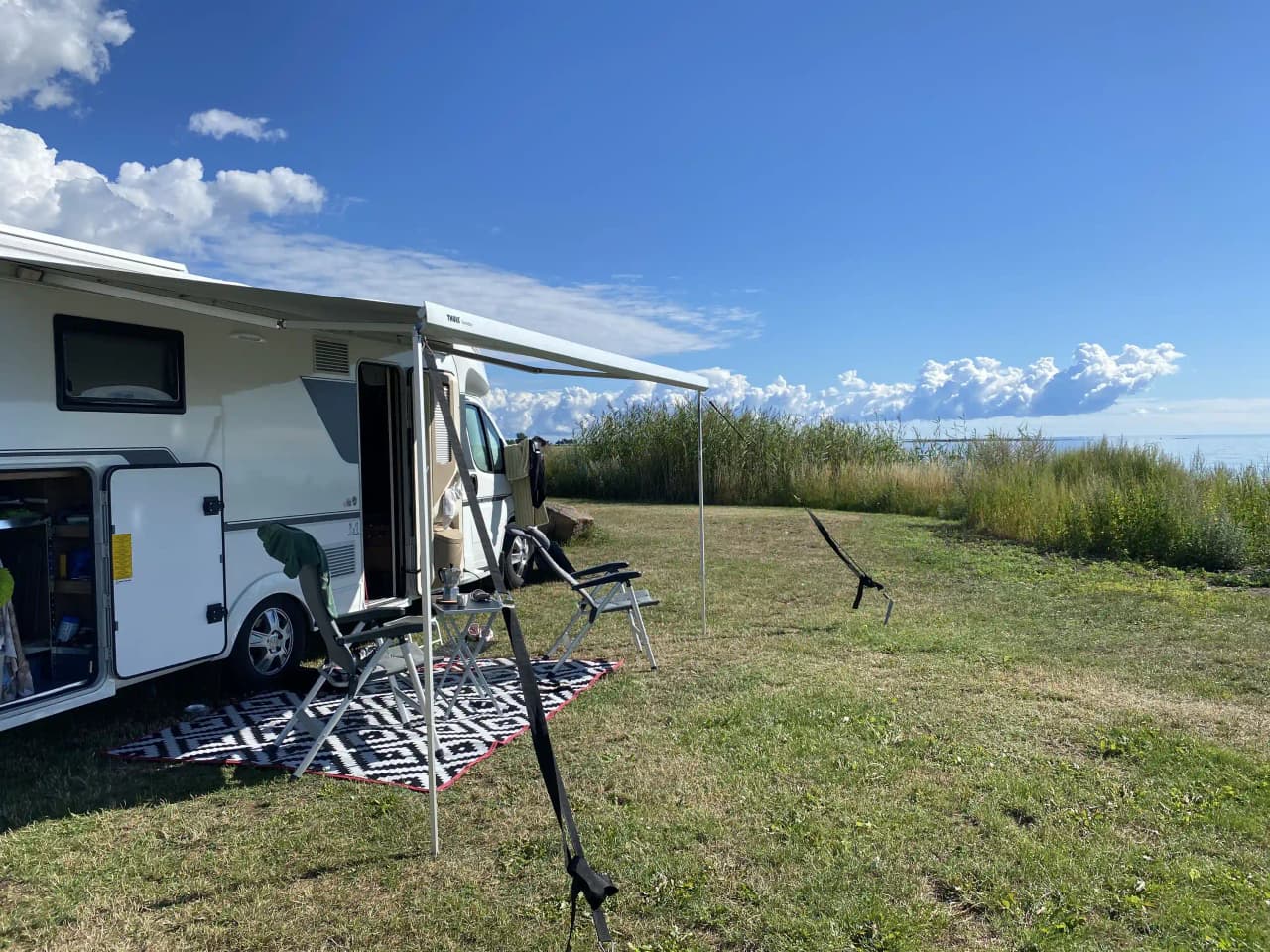En husvagn uppställd på en campingplats omgiven av gröna träd och gräs, en typisk scen vid Björkenäs camping.