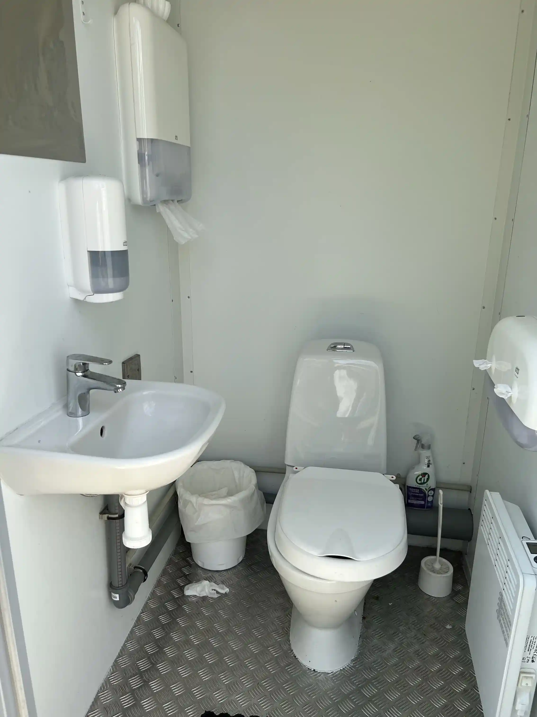 En bild av en toalettstol och handfat i ett badrum med kakelgolv på Björkenäs camping.