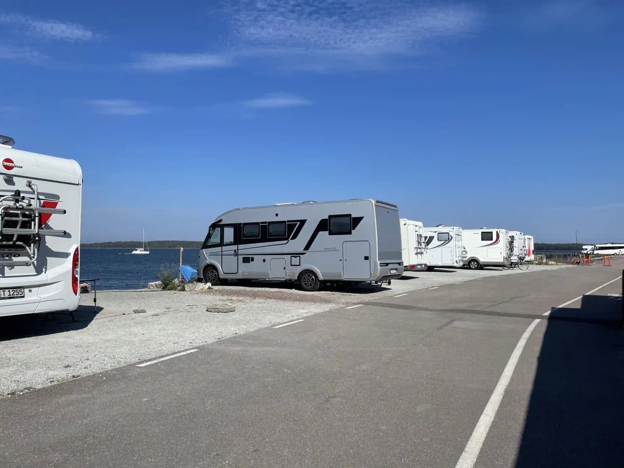 Ett stort campingområde vid Böda Hamn med flera uppställda husvagnar och husbilar. Parkeringen är fylld med fordon, inklusive lastbilar och transportbilar, vilket skapar en livlig atmosfär av semestergäster och campingliv.