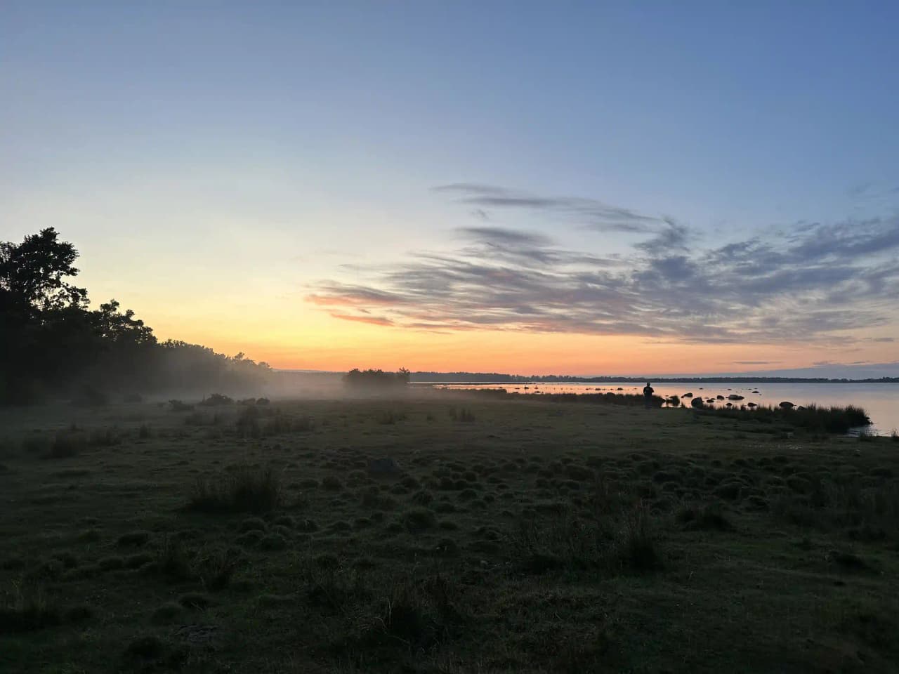 Solnedgång över Böda hamns camping med ett färgrikt himmelslandskap och mjuka moln ovanför horisonten.