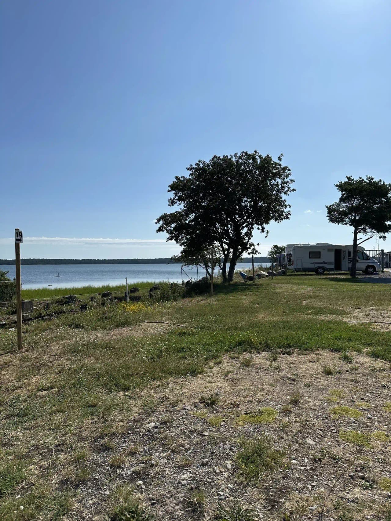 En husbil parkerad nära en lång sandstrand vid kusten på Böda Hamns Camping, med öppet hav i bakgrunden.