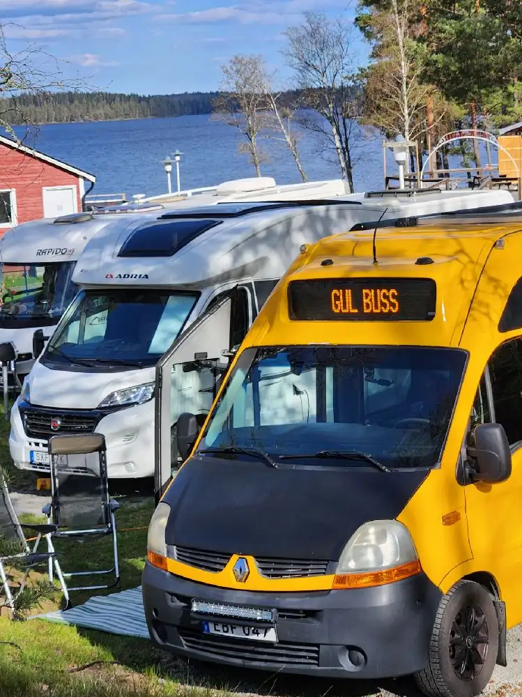 En kompakt husbil parkerad vid Uvaparken ställplats, omgiven av grönskande natur.