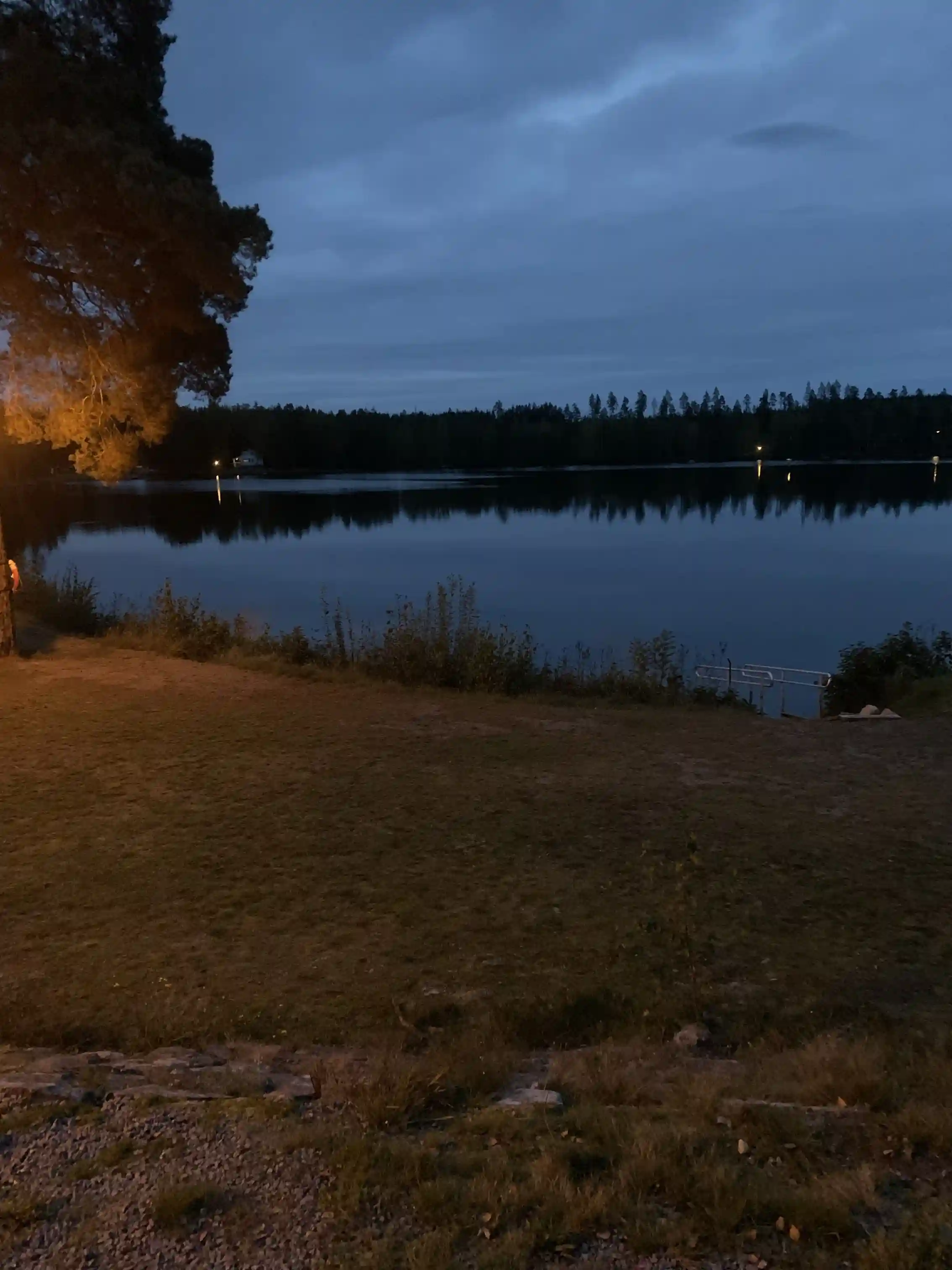 Vy över vattenresurser i uvaparken ställplats vid skymningen, med en glittrande vattenyta och en horisont som möter kvällshimlen. Naturlig miljö omger platsen, vilket ger en lugn och avkopplande atmosfär.