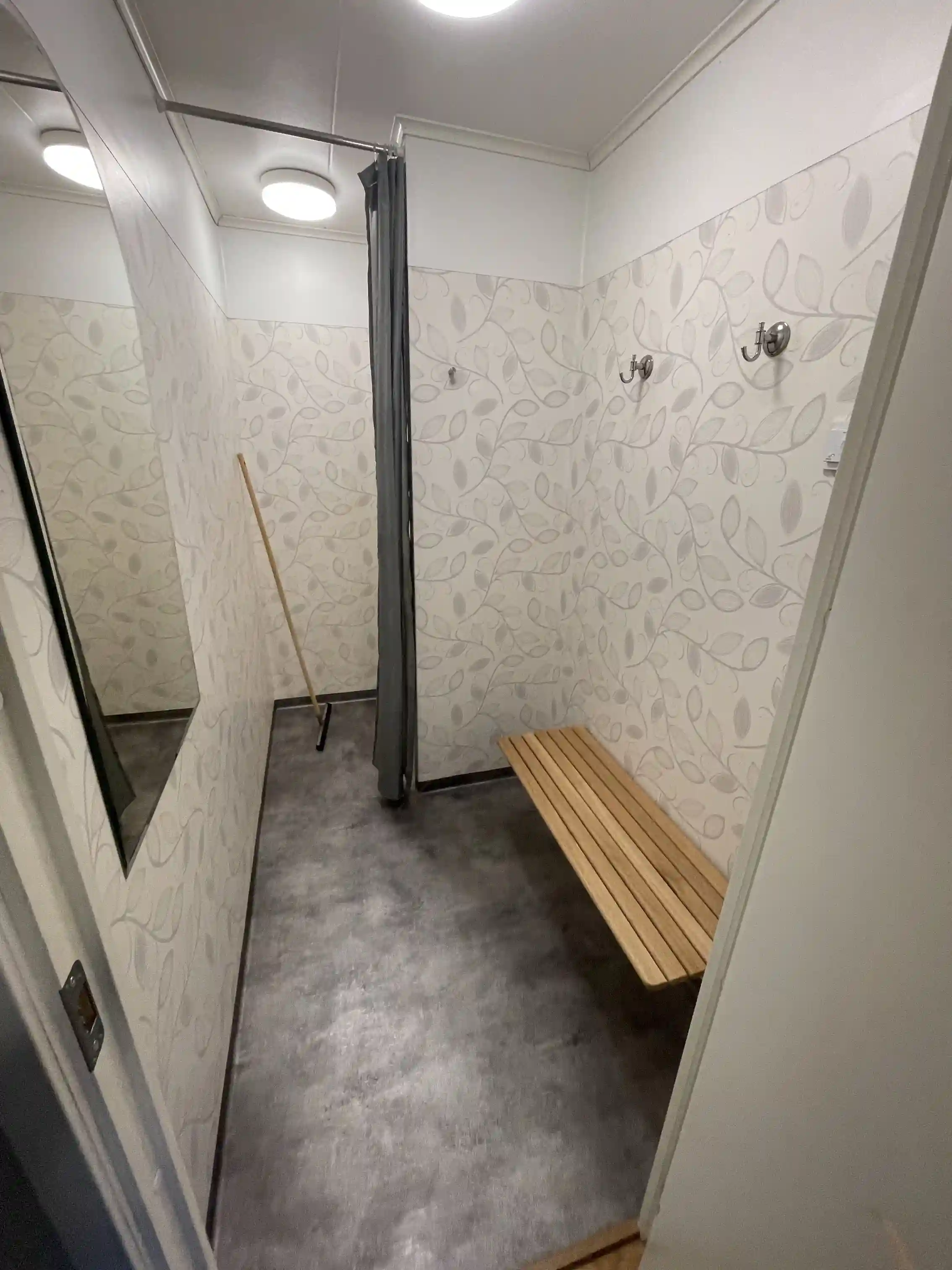 Bild av Uvaparken Ställplats med interiör som visar golv och tak i grå nyans, kakelgolv och tak, samt detaljer i silver och trä.