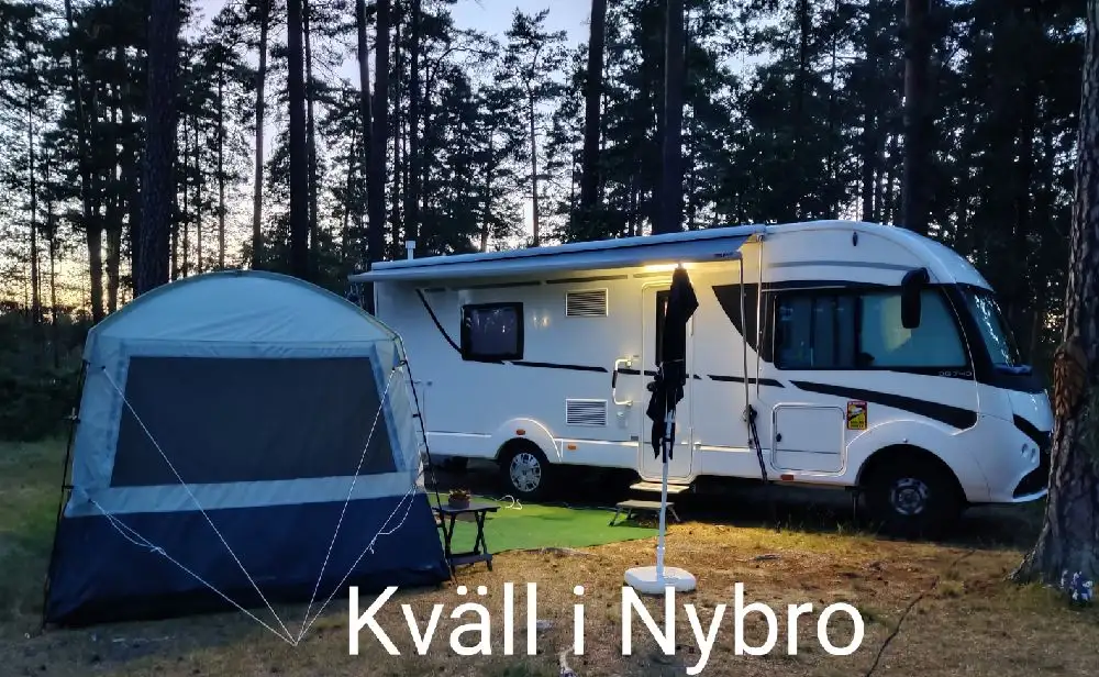 En husbil och en husvagn parkerade på Joelskogens camping & ställplats, omgivna av grönska.