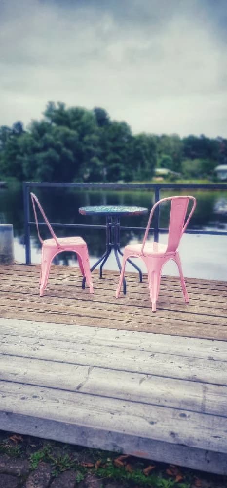 En cykel med metallram står lutad mot ett staket utomhus, omgiven av campingmöbler.