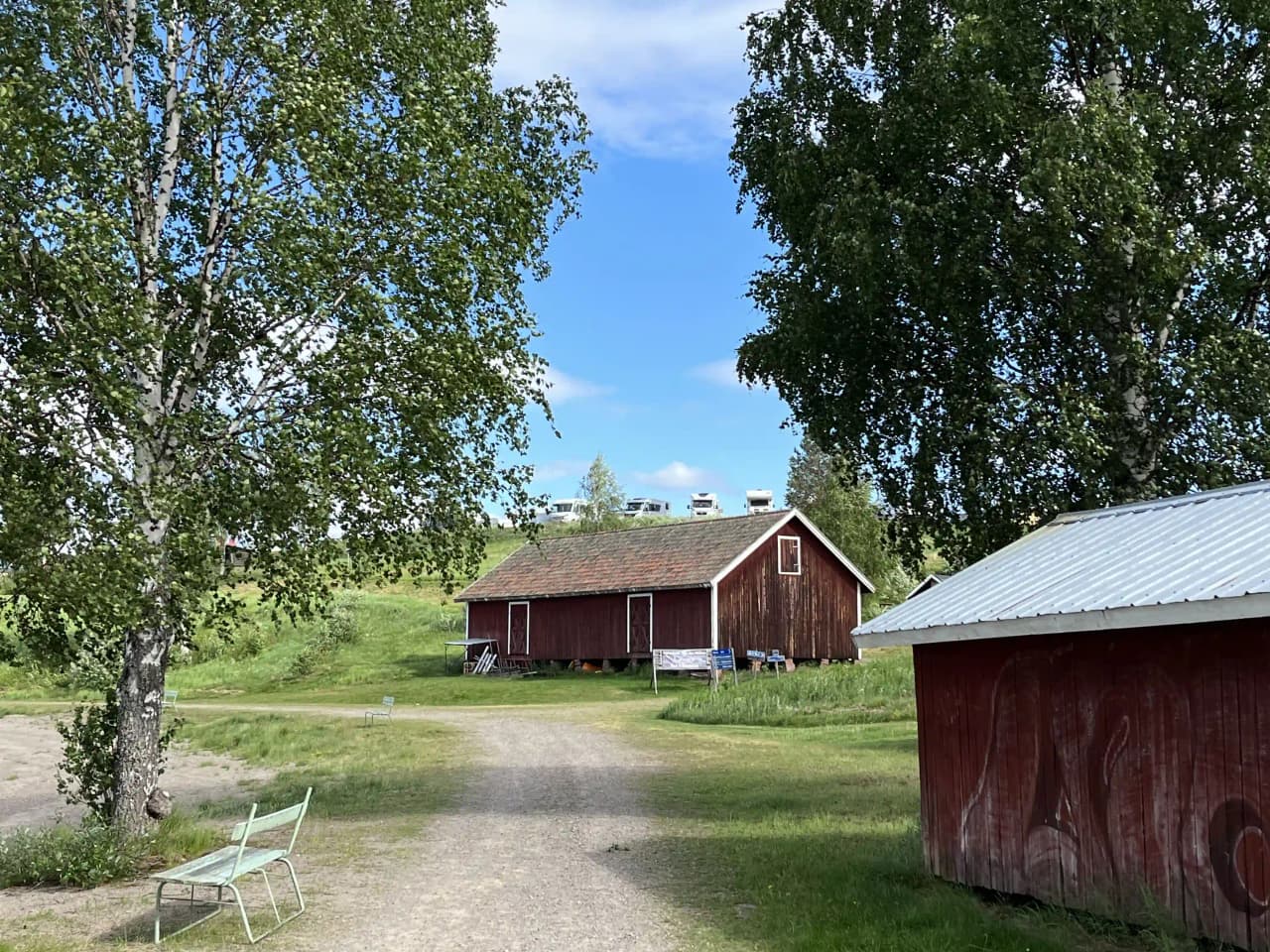 En lantlig campingplats i Särna med gräsfält och träd omkring en stuga. Huis i sverige.