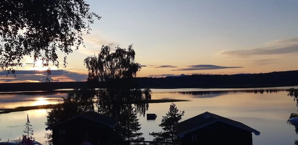 En vacker kvällsvy vid Särna Camping med solnedgångens färger som speglas i den stilla sjön.