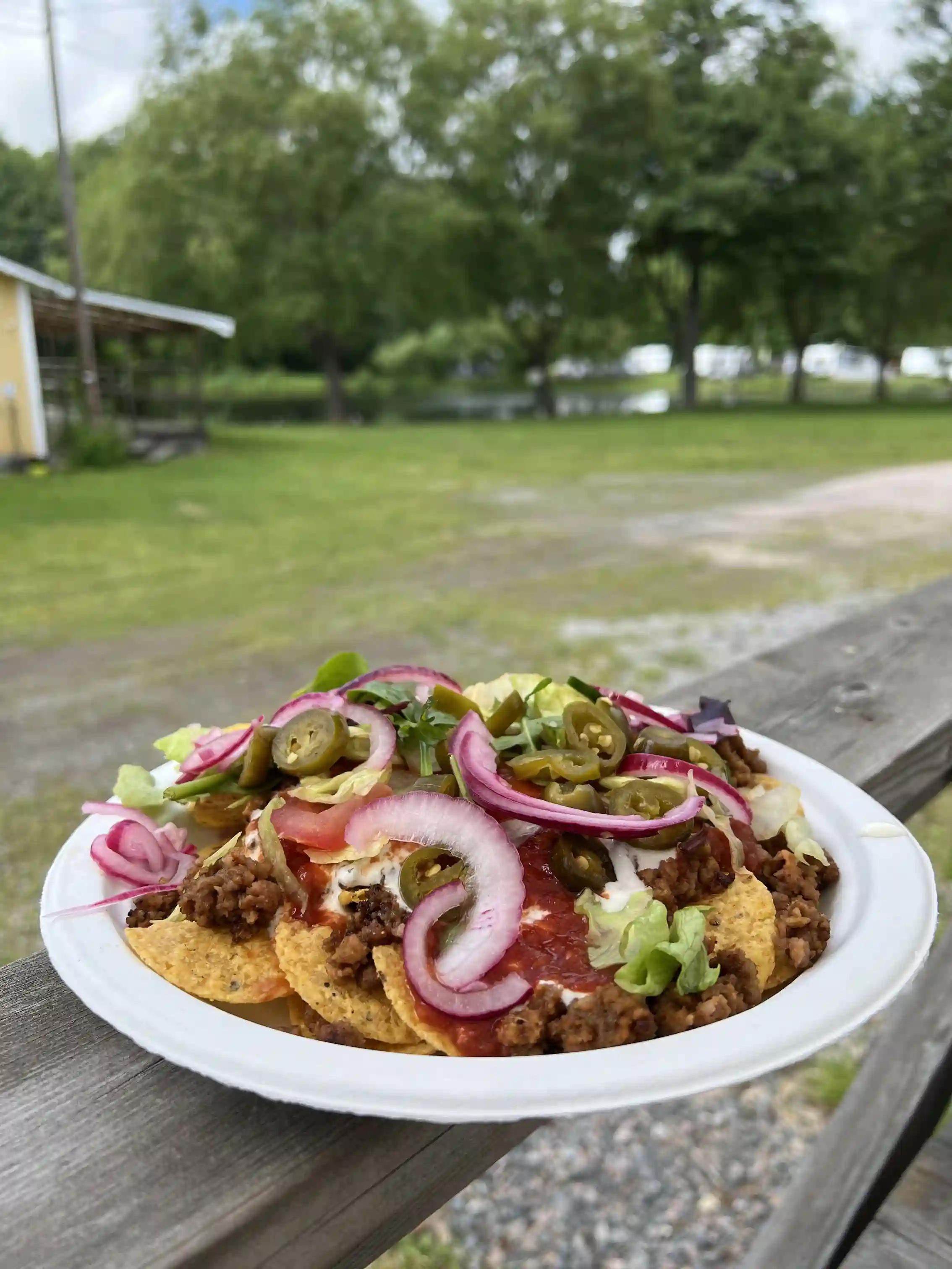 En aptitretande sallad med fräscha grönsaker och skivor av kött, uppdukad på ett träbord. Perfekt för ett måltidsstopp på Simbadets camping.