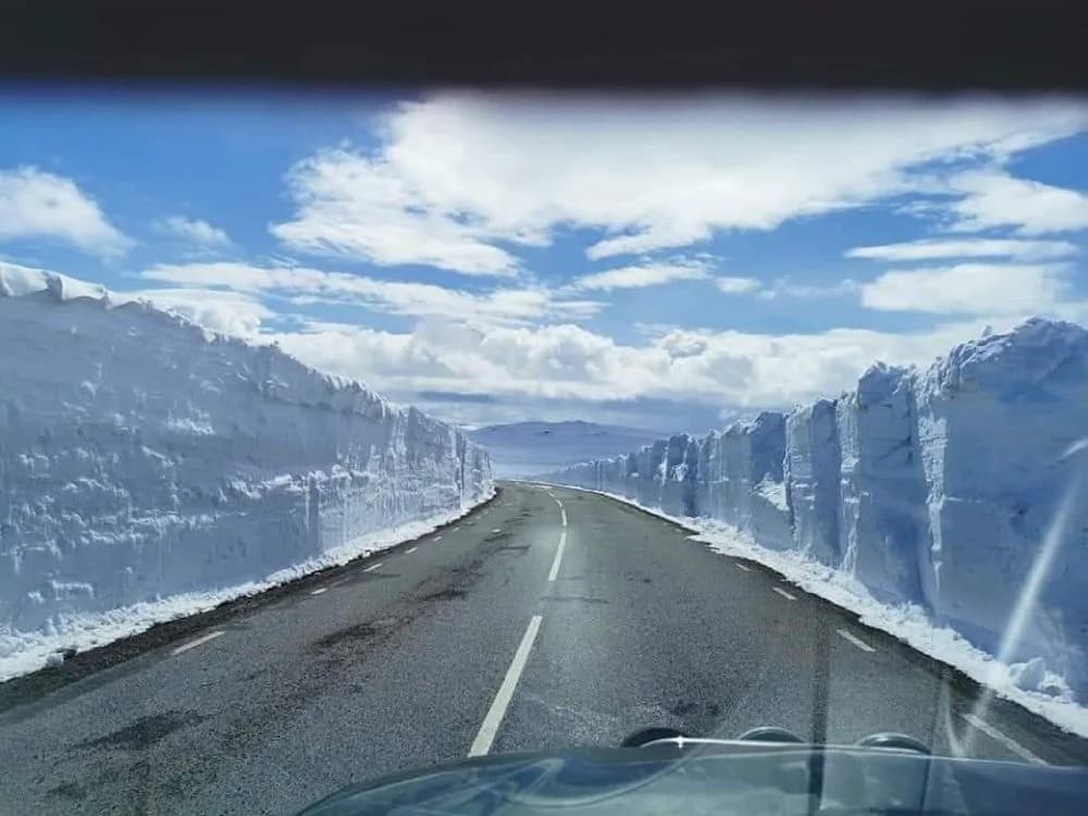 Bild av Hotel Nordica i en vintrig miljö, med en asfalterad väg som leder mot hotellet. Snö täcker marken och bergen i bakgrunden, vilket skapar en fridfull atmosfär.