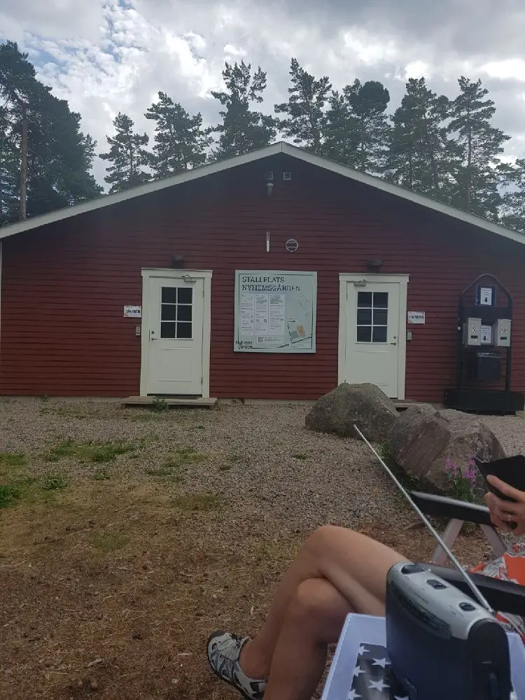 En välskött trädgård framför en traditionell fasad med träpaneler på Nyhemsgården.