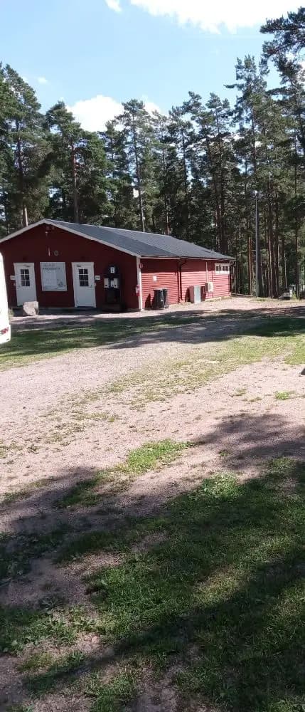 En grusuppfart leder fram till Nyhemsgården. Gården omges av en grön gräsmatta och lummiga träd som skapar skugga i trädgården. En fridfull och inbjudande atmosfär råder.
