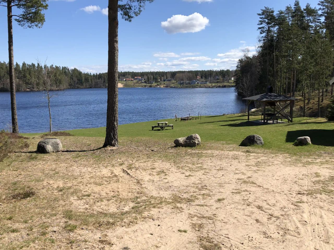 En naturskön utsikt över en sjö omgiven av frodiga grönområden vid Nyhemsgården.