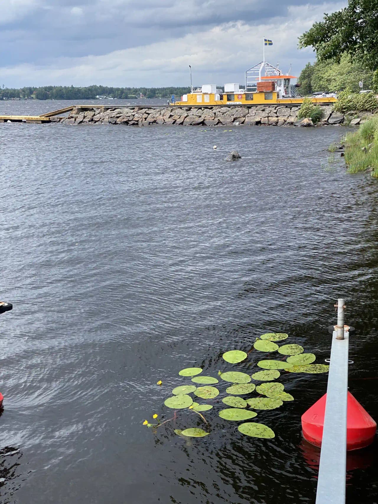 En roddbåt ligger förtöjd vid ett stilla vattendrag, omgiven av grönska och spegelblanka vattenytor, vilket skapar en fridfull och naturnära atmosfär vid Hägern Bed & Nature.