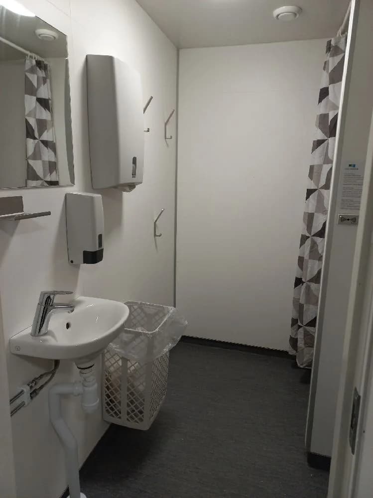 En ljus och fräsch badrumsinteriör med klinkergolv och vita kakelväggar. I mitten av bilden syns ett modernt handfat med en kromblandare.