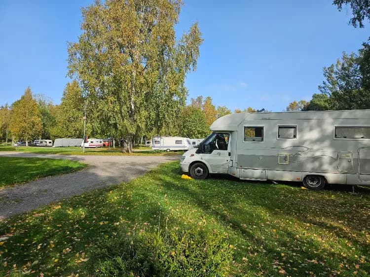 En campingplats vid Gålö Havsbad med flera uppställda husvagnar och husbilar omgivna av grönska, redo för campinggäster och naturälskare.