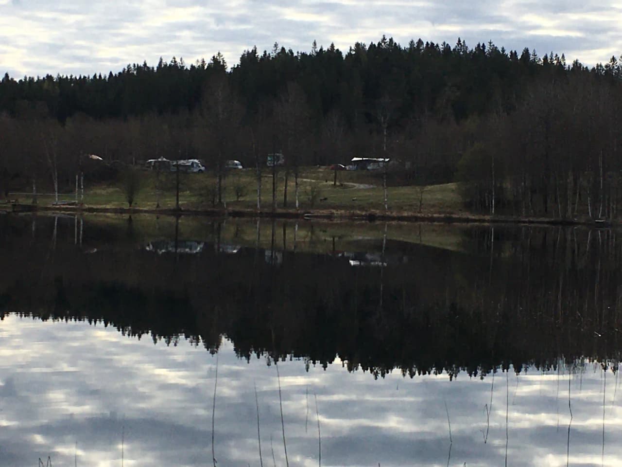 En lugn sjö med spegelblank yta som reflekterar den omgivande naturen vid Påarps Gård.