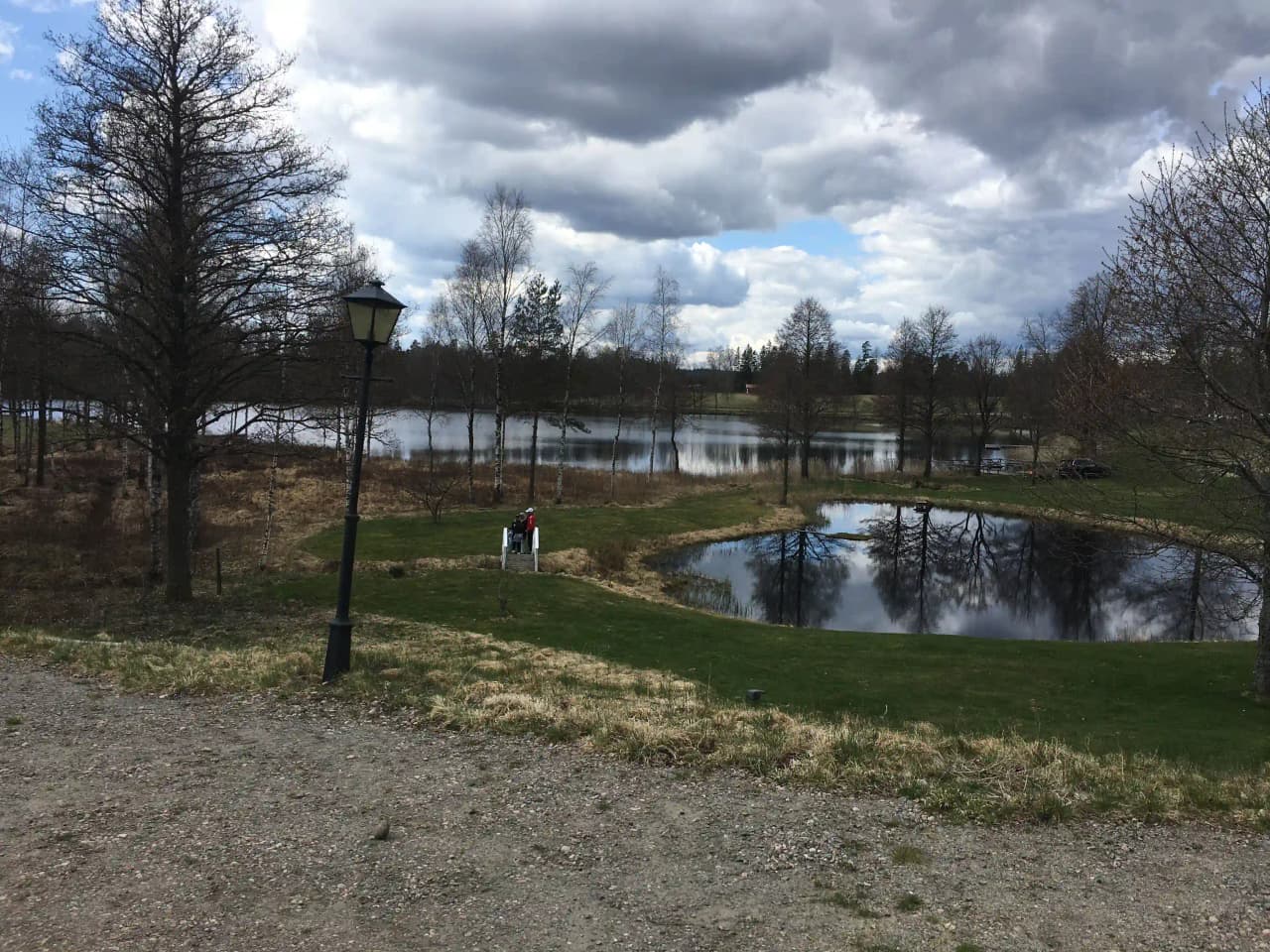 En lugn vattenyta omgiven av frodig grönska och träd på Påarps gård, med reflektioner av naturen i vattnet.