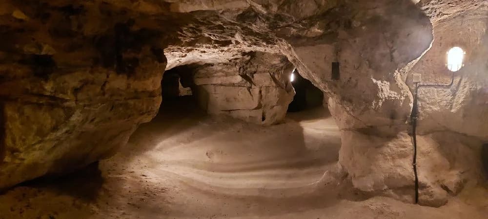 En grottöppning med naturliga bergformationer och erosionstecken vid Tykarpsgrottans camping.