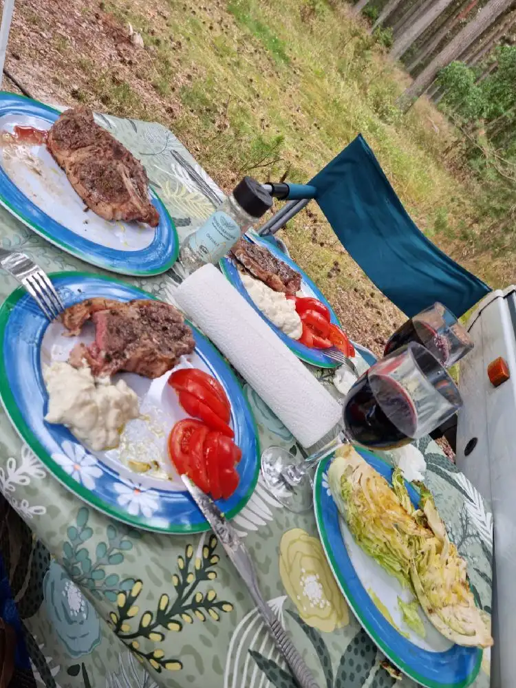 Ett bord uppdukat med porslin och serveringsfat, innehållande olika maträtter och drycker. Fokus ligger på frukostingredienser och köksredskap, vilket ger en inbjudande och hemtrevlig atmosfär på Åhus Missionsgård.
