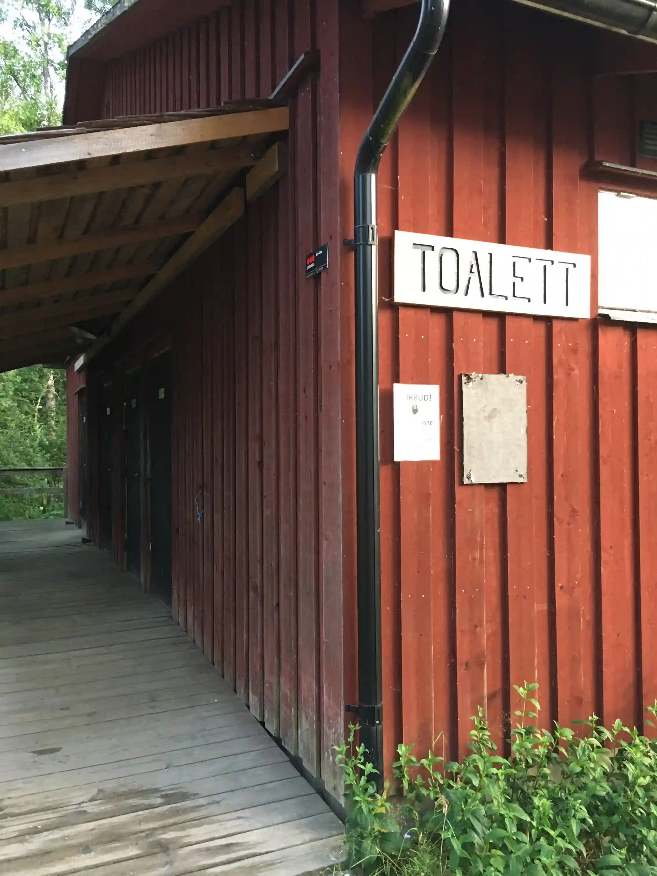 En bild av Brunskog Hembygdsgård som visar en traditionell byggnad med träfasad. Byggnaden påminner om en timmerstuga, omgiven av grönska.