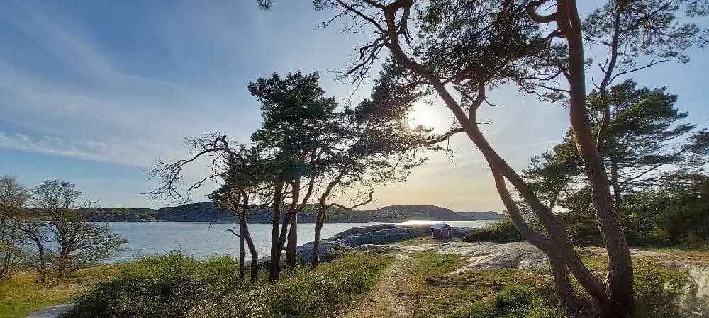 Bild av fjällbacka camping vid en vattenkant, omgiven av steniga kuster och vildmark. Den natursköna utsikten över en sjö skapar en idyllisk och rofylld atmosfär.