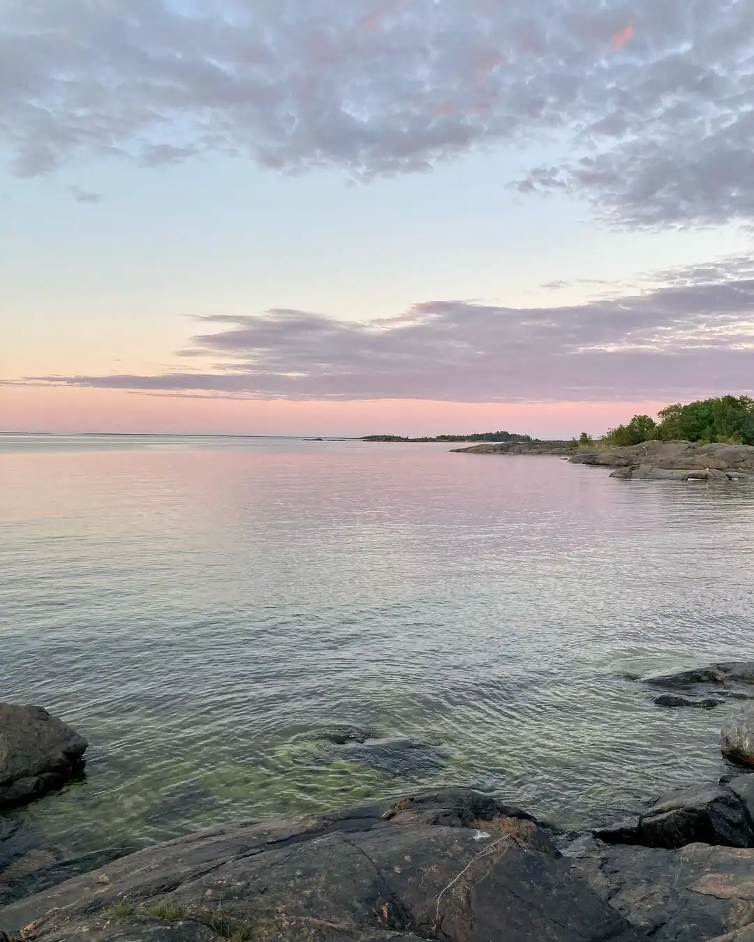 En vacker havsutsikt vid Ängskärs havscamping med klarblå himmel, stilla vatten och klippiga kuster i horisonten.