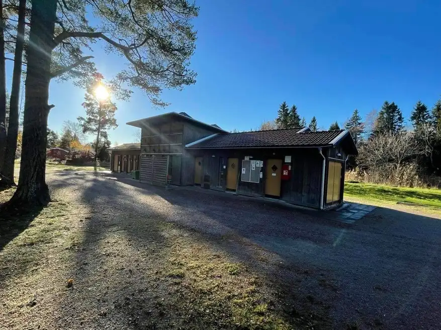 En lantlig campingplats med stugor omgivna av gröna träd och asfaltvägar.