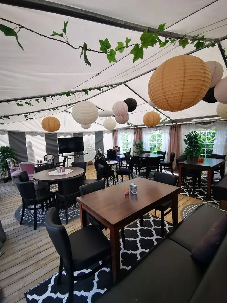 Alt-text: Uteservering vid Bovikens Havsbad med träbord och stolar, belägen i en inbjudande miljö för avkoppling och måltider nära havet.