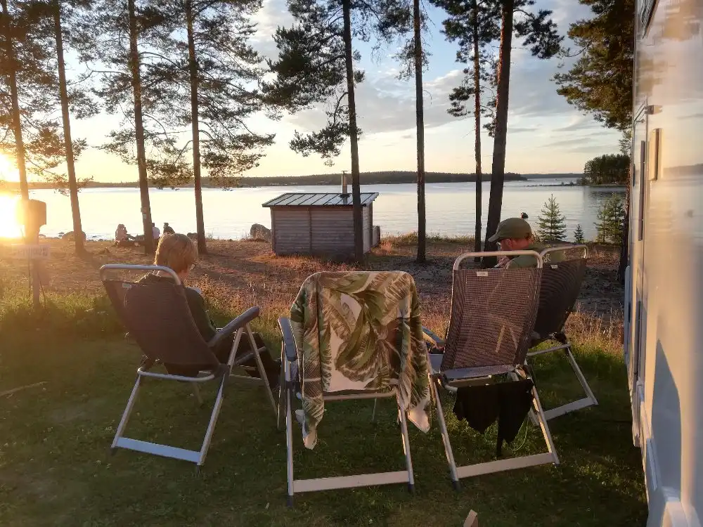 En solig dag vid Bovikens havsbad med utemöbler, inklusive stolar och ett bord, som skapar en inbjudande plats för vila och samkväm i trädgårdsmiljön.