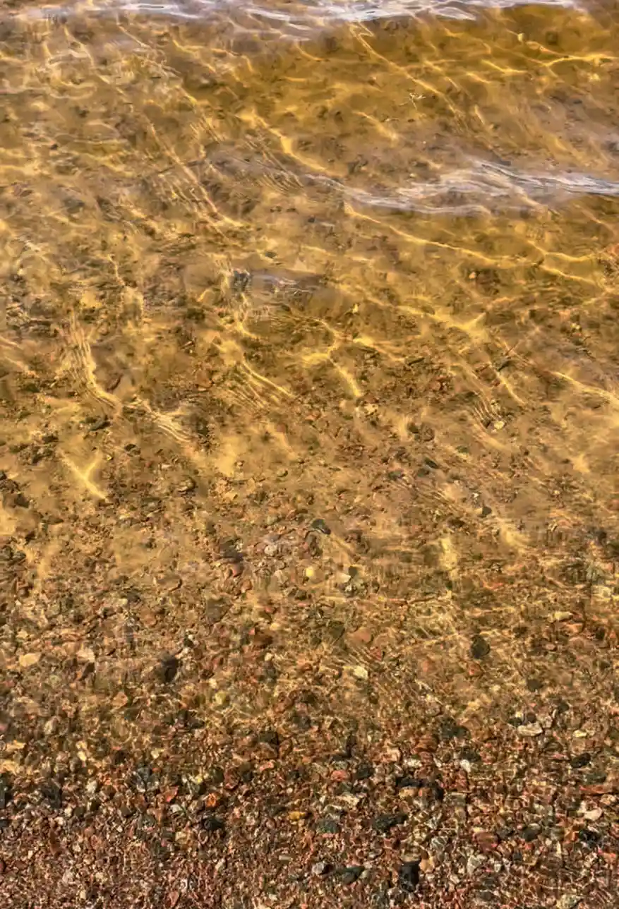 En sandstrand vid Säters camping med en brun nyans i bakgrunden.