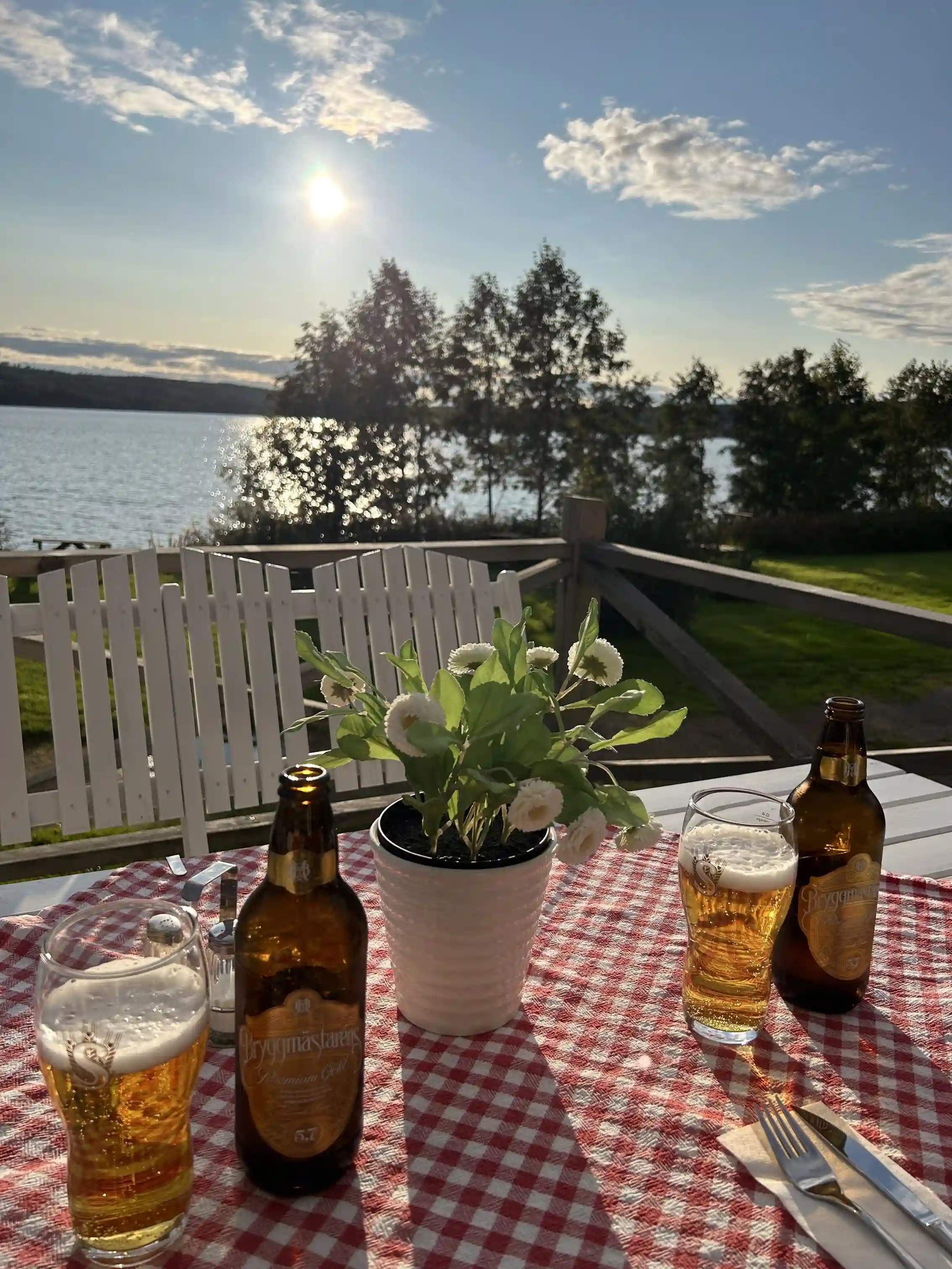 En uteservering vid Säters camping med bord och stolar, dukat med glas och bestick, redo för servering av mat och dryck.